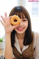 A woman holding a donut in front of her face.