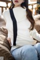 a woman sitting on top of a couch wearing a white sweater