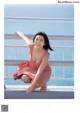 A woman in a pink dress sitting on a railing.