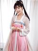 A woman in a pink and white hanbok is posing for a picture.