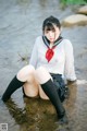 A woman in a school uniform is sitting in the water.