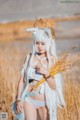 A woman in a white outfit holding a bunch of wheat.