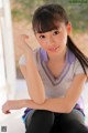 A young woman sitting on the floor with her hand on her chin.