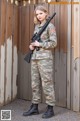 A woman in a military uniform holding a rifle.