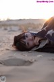 A woman laying on the sand under a blanket.