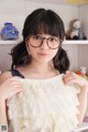 A woman wearing glasses standing in front of a shelf.