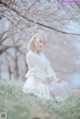 A woman in a white dress sitting in the grass.