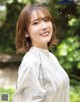 A woman in a white blouse smiles at the camera.